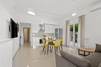 a kitchen and living room with a table and yellow chairs at Palea Luxury Living in Galatás