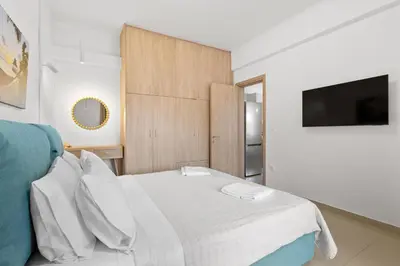 a bedroom with a white bed and a television at Palea Luxury Living in Galatás