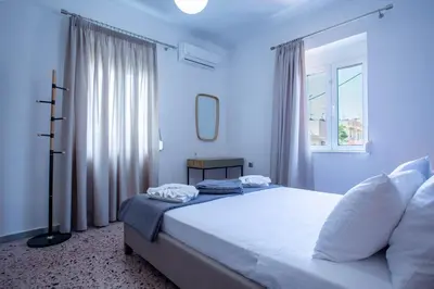a bedroom with a bed with white sheets and a window at Be Crete - Villa Del Sol in Chania Town