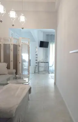 a white living room with a couch and a tv at Chania Town Center with Balcony by MPS in Chania Town