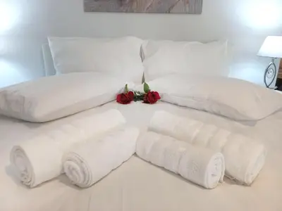 a group of white pillows and red roses on a bed at Chania Town Center with Balcony by MPS in Chania Town