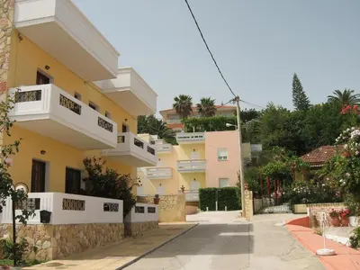 a yellow building with white balconies on a street at Anniko in Stalos