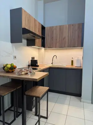 a kitchen with wooden cabinets and a table with a bowl of fruit at Unique Apartment 3 in Chania Town