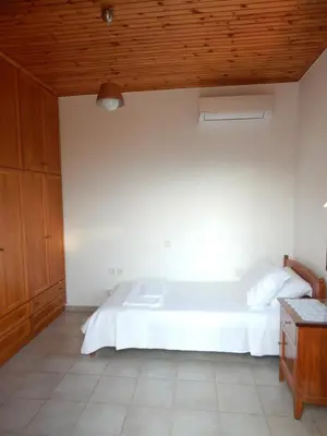a bedroom with a white bed and a wooden ceiling at Kaina Villa in Vamos