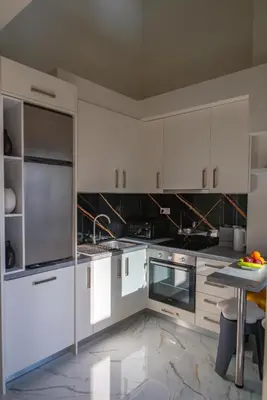 a kitchen with white cabinets and a table in it at Thalo Maison in Chania Town