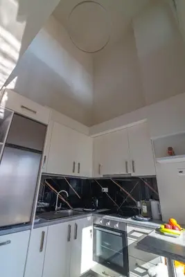 a kitchen with white cabinets and a black counter top at Thalo Maison in Chania Town