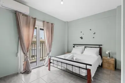 a white bedroom with a bed and a window at Litsa's Maisonette Near Sea - City Center in Chania Town