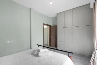 a white bedroom with a bed and a mirror at Litsa's Maisonette Near Sea - City Center in Chania Town