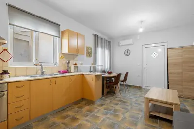 a kitchen with wooden cabinets and a table at Litsa's Maisonette Near Sea - City Center in Chania Town