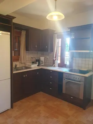 a kitchen with brown cabinets and a white appliance at Villa Eudokia Terrace Views Pool in Douliana