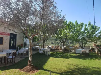 a yard with tables and chairs and a tree at Villa Eudokia Terrace Views Pool in Douliana