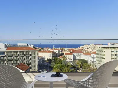 a view of a city from a balcony with a table and chairs at Hilton Garden Inn Chania City in Chania Town