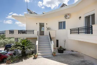 a white house with stairs and a driveway at Olive Ηouse, Quiet, Cozy, mountain view, family in Milonianá