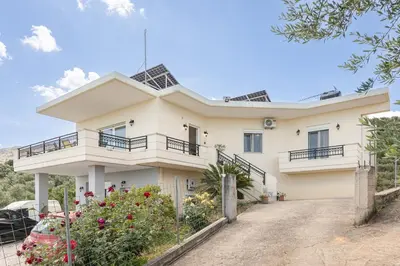 a large white house with a driveway at Olive Ηouse, Quiet, Cozy, mountain view, family in Milonianá