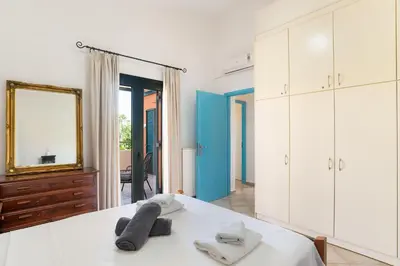 a bedroom with a bed with a mirror and white cabinets at Villa Calista In Aspro -BY APOKORONAS VILLAS in Koprána
