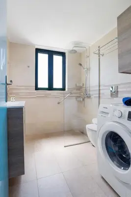 a bathroom with a washing machine and a toilet at Villa Calista In Aspro -BY APOKORONAS VILLAS in Koprána