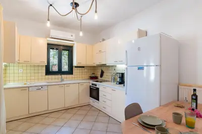a kitchen with a white refrigerator and a table at Villa Calista In Aspro -BY APOKORONAS VILLAS in Koprána