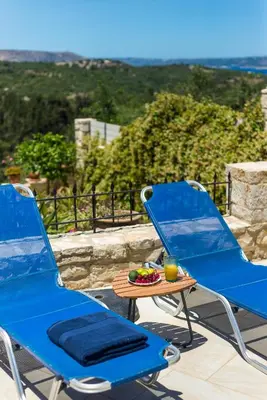 two blue chairs and a table on a patio at Villa Calista In Aspro -BY APOKORONAS VILLAS in Koprána