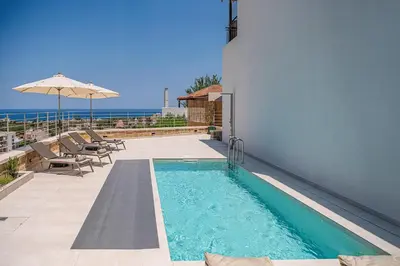 a swimming pool next to a building with an umbrella at Petra Retreat Residence in Daratso