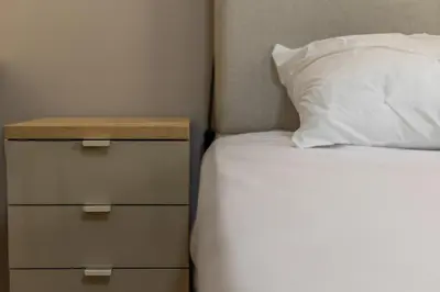 a bed with a white pillow and a night stand at Architects Oasis in Chania Town