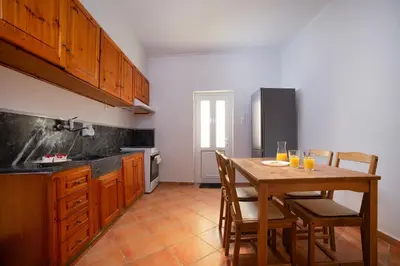 a kitchen with a wooden table with chairs and a kitchen with a refrigerator at Artemis House in Chania Town