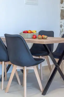 a wooden table with two chairs and a bowl of fruit at Liastera Luxury Apartments in Áyios Fótios