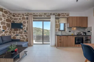 a kitchen and living room with a stone wall at Liastera Luxury Apartments in Áyios Fótios