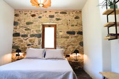 a bedroom with a stone wall and a bed at Mozaik House