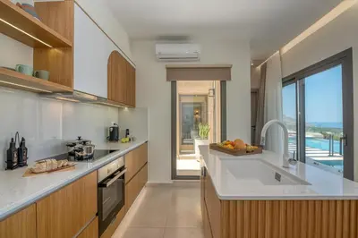 a kitchen with white counters and a view of the ocean at Villa Tierra in Kissamos