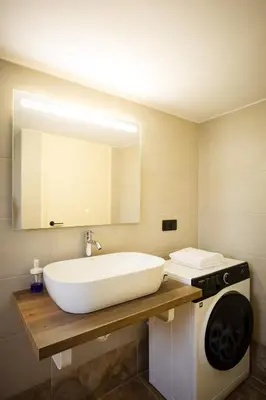 a bathroom with a white sink and a washing machine at Mantarini House in Chania Town