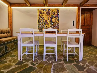 a table with four chairs and a painting on the wall at BROWN ON GREEN a stone house with amazing view in Drapaniás