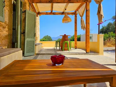 a wooden table with a vase on top of it on a patio at BROWN ON GREEN a stone house with amazing view in Drapaniás