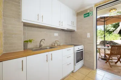 a kitchen with white cabinets and a sink at Galatas Maisonette in Galatás