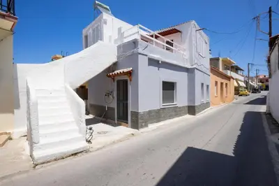 a white building with stairs on the side of a street at Galatas Maisonette in Galatás