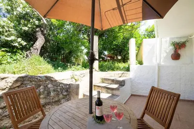 a table with wine glasses and an umbrella on a patio at Galatas Maisonette in Galatás