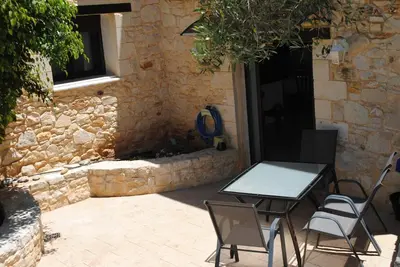 a table and chairs in front of a stone building at Stone House by the Sea in Tavronitis