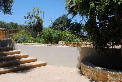 a stone retaining wall with a staircase in a garden at Stone House by the Sea in Tavronitis