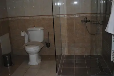 a bathroom with a toilet and a glass shower at Stone House by the Sea in Tavronitis