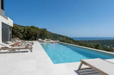 a swimming pool with chaise lounges and chairs on a building at Ataraxia Villa in Spiliá