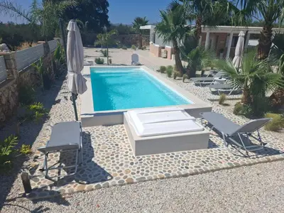 a swimming pool with two chairs and an umbrella at Villa Dadis in Chania