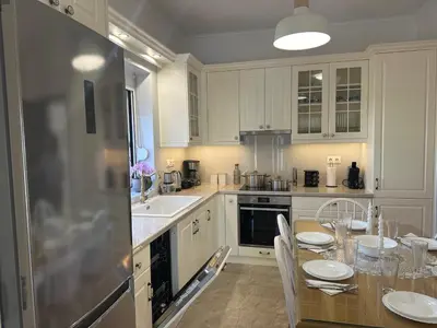 a kitchen with white cabinets and a table with chairs at Vila Alexandros in Souda
