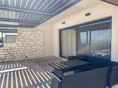 a patio with a table and chairs and a window at Gialos Villas Paleochora in Palaiochóra