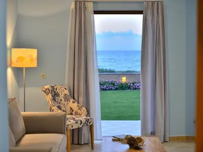 a living room with a chair and a view of the ocean at Niriides Apartments in Kissamos