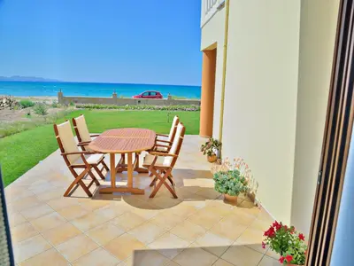 a patio with a table and chairs and the ocean at Niriides Apartments in Kissamos