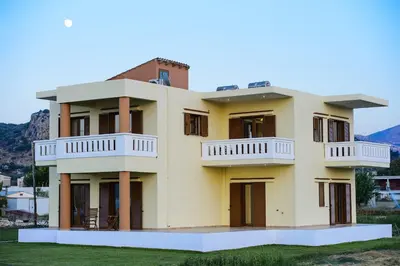 a large yellow house with balconies on top at Niriides Apartments in Kissamos