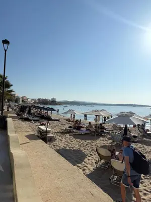 a man walking on a beach with people sitting on chairs and umbrellas at Casa di Keti in Chania Town