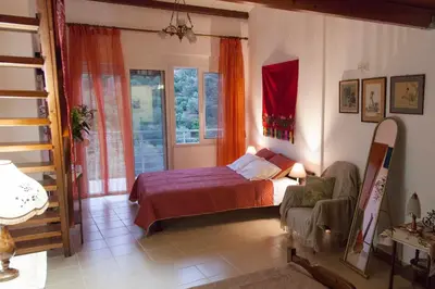 a bedroom with a bed and a chair and a window at Villa Olea-Renieri in Grigorianá