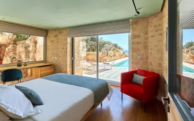 a bedroom with a bed and a red chair at New Luxury Olives & Thyme Retreat, Seaview with 2 Heated Pools in Chania Town