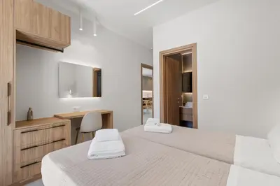 a white bedroom with two beds and a desk at Sea Princessa Villa in Chania Town
