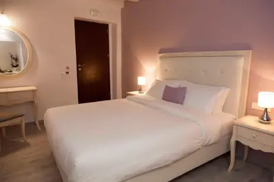 a bedroom with a large white bed and a mirror at Shalom Luxury Rooms Kondilaki in Chania Town